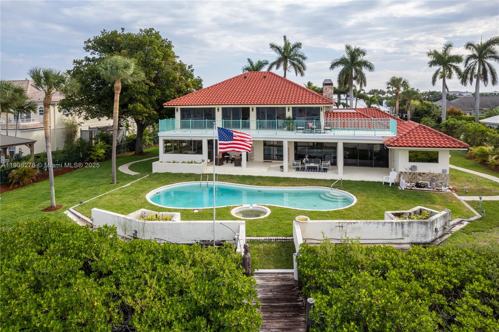 An aerial view shows a two-story house with a red tile roof, pool, and flag — 1635 Lands End Rd, Manalapan FL 33462, MANALAPAN, FL