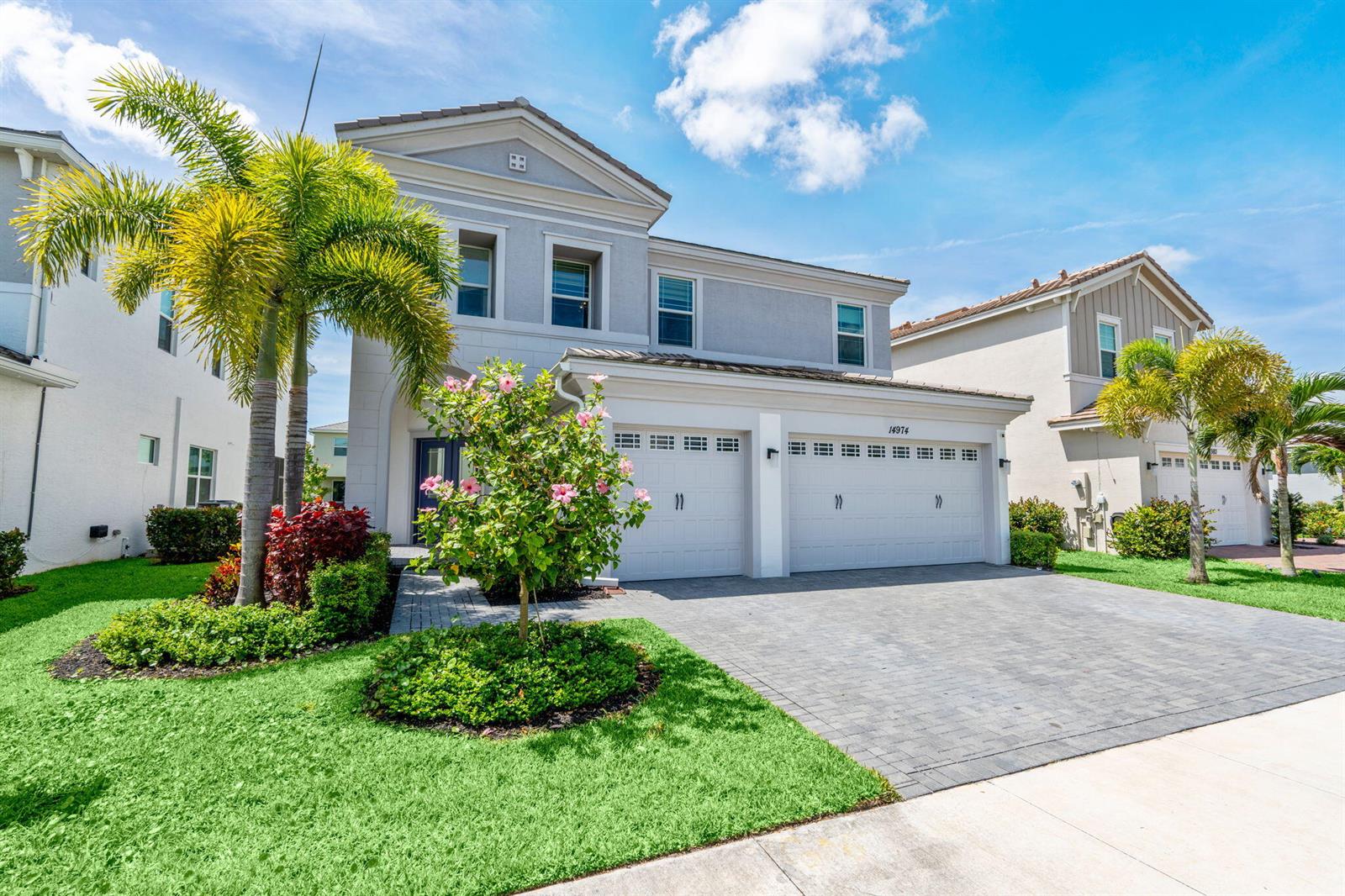 A two-story suburban house features a paved driveway, a three-car garage, and palm trees — 14974 Goldspar Court, Westlake FL 33470, WESTLAKE, FL