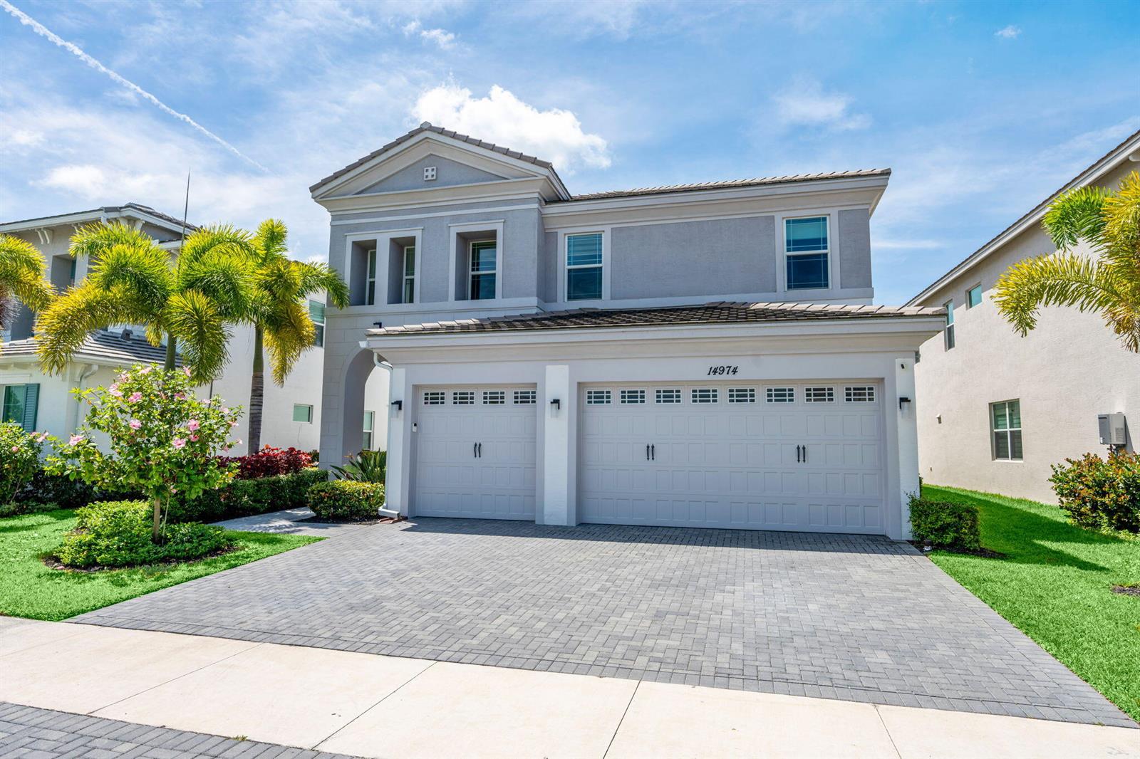 A two-story house with a three-car garage and a paved driveway under a blue sky — 14974 Goldspar Court, Westlake FL 33470, WESTLAKE, FL