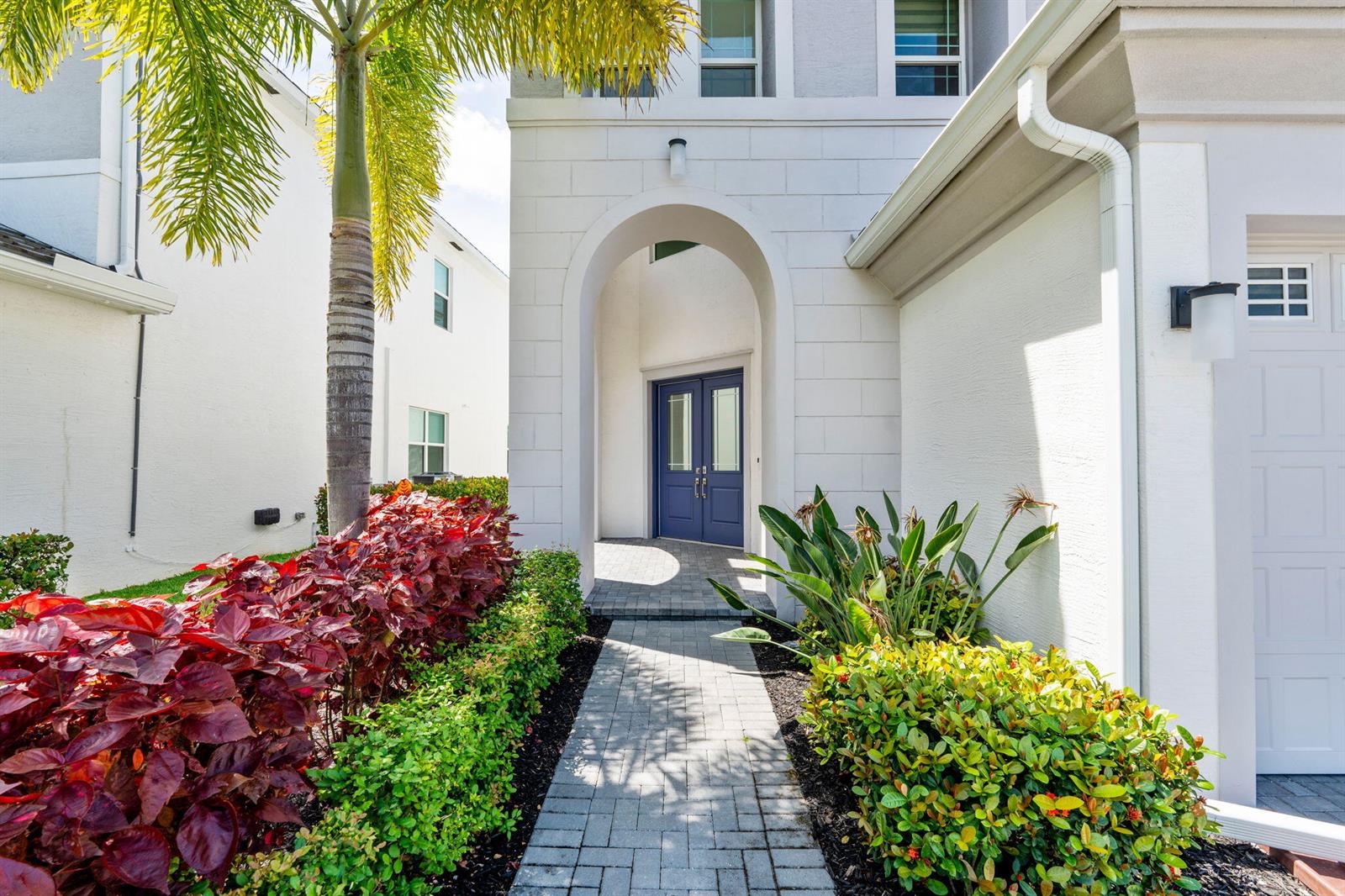 A paved walkway leads to a blue double front door under a white arched entryway — 14974 Goldspar Court, Westlake FL 33470, WESTLAKE, FL