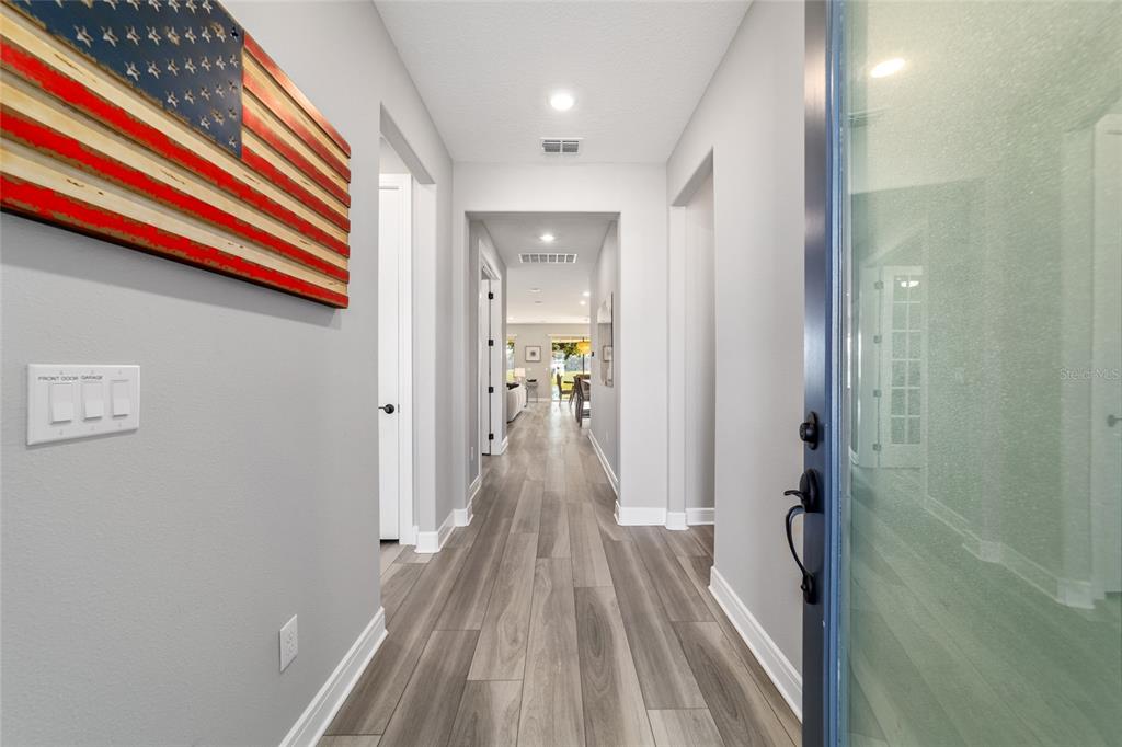 A view from an entryway looking down a hallway with wood-look flooring and gray walls — 5740 SW 90TH COURT ROAD, OCALA, FL