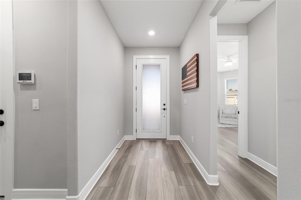 A bright entryway features light wood-look flooring, gray walls, and a white frosted glass door — 5740 SW 90TH COURT ROAD, OCALA, FL