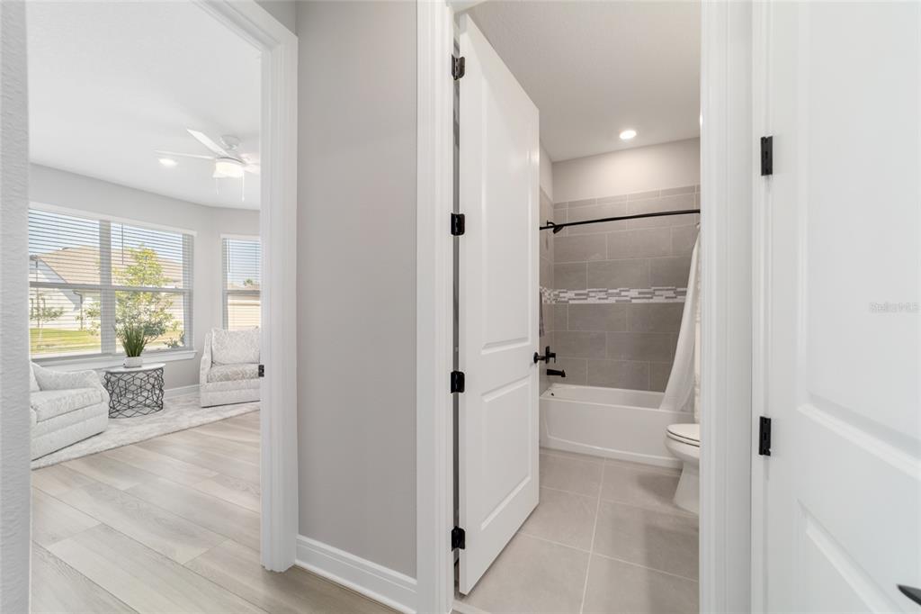 A hallway view shows a bedroom with light wood floors and an adjacent tiled bathroom — 5740 SW 90TH COURT ROAD, OCALA, FL