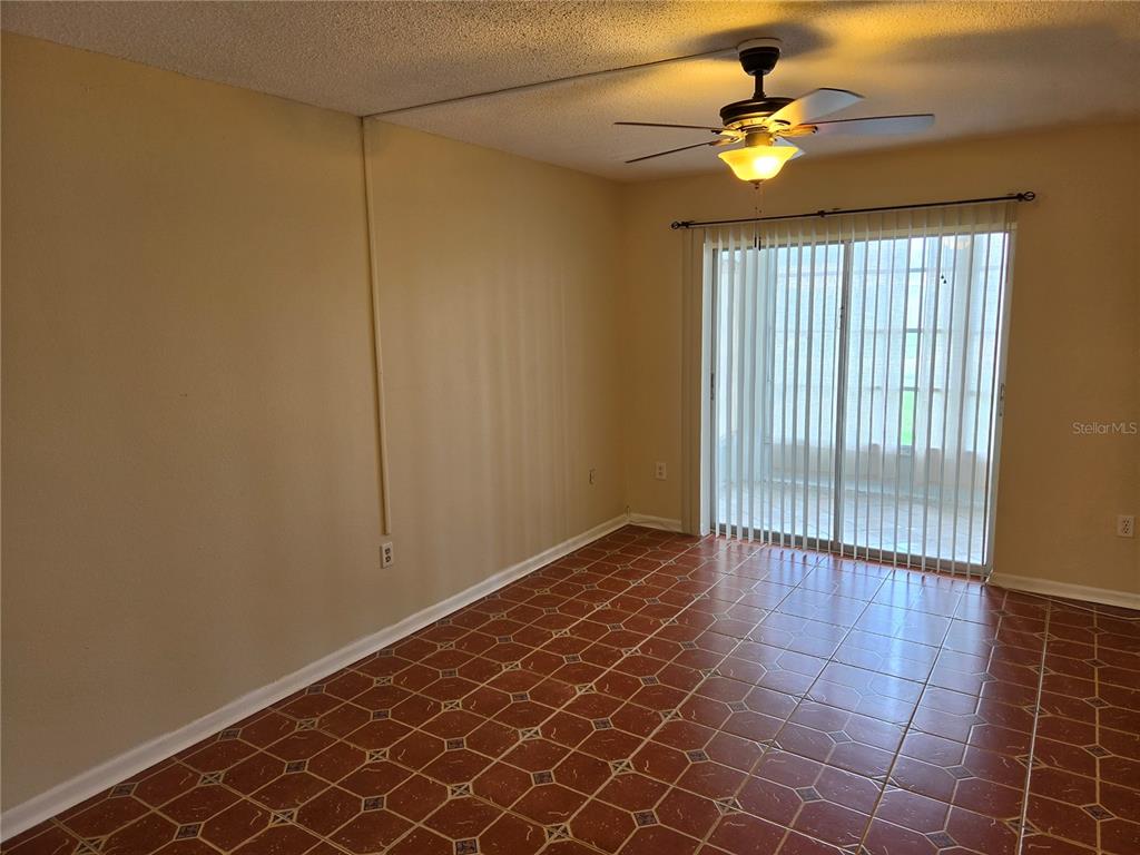 An empty room with terracotta tile flooring, a ceiling fan, and sliding glass patio doors — 10351 REGAL DRIVE UNIT 3, LARGO, FL