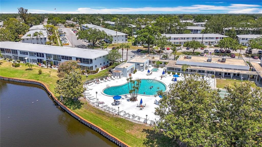 An aerial view shows a swimming pool, a lake, and multi-story residential apartment buildings — 8305 111TH STREET UNIT 108, SEMINOLE, FL
