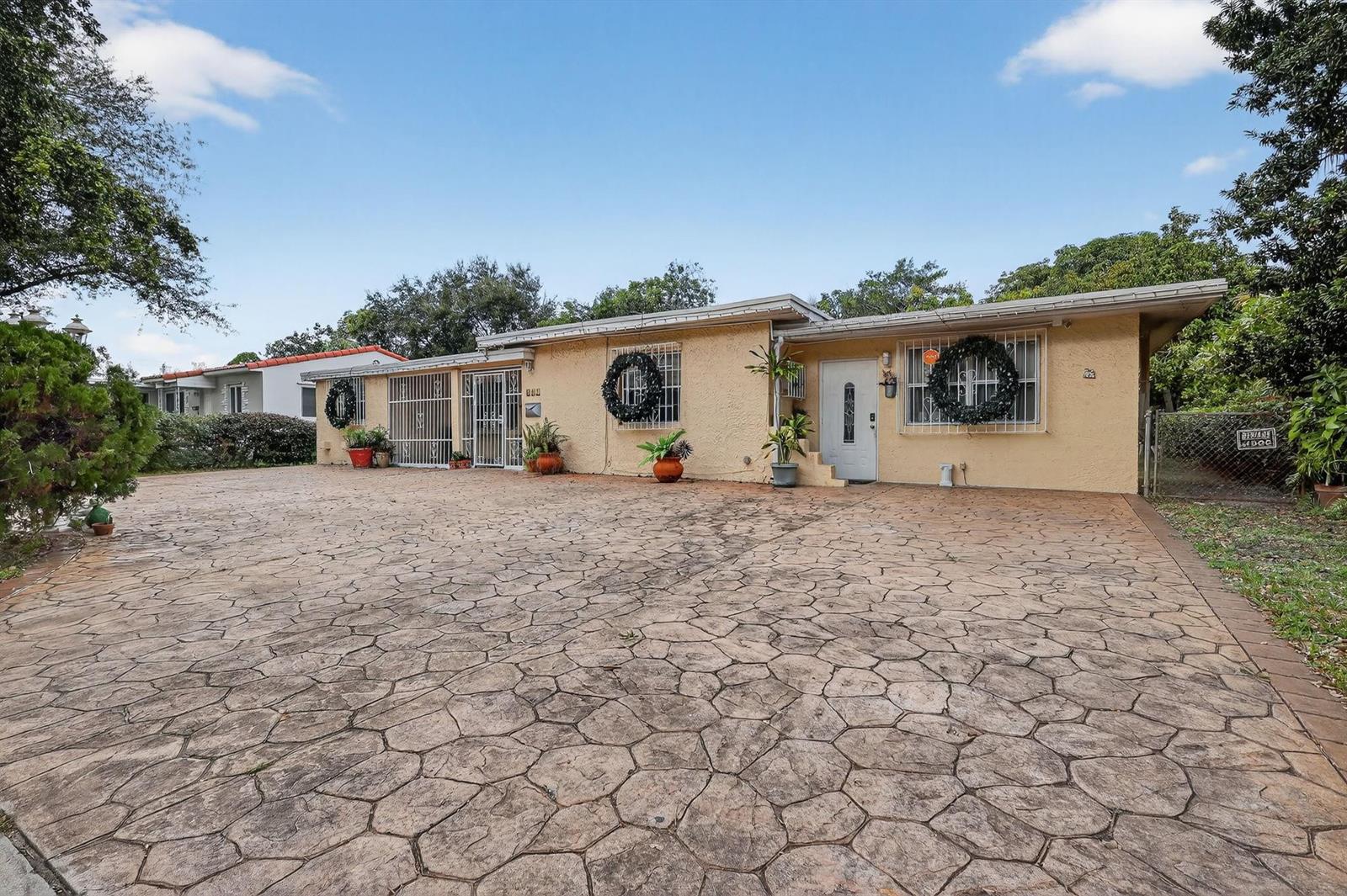 A single-story house with a large stamped concrete driveway and security bars on the windows — 641 NE 140th Street, North Miami FL 33161, NORTH MIAMI, FL