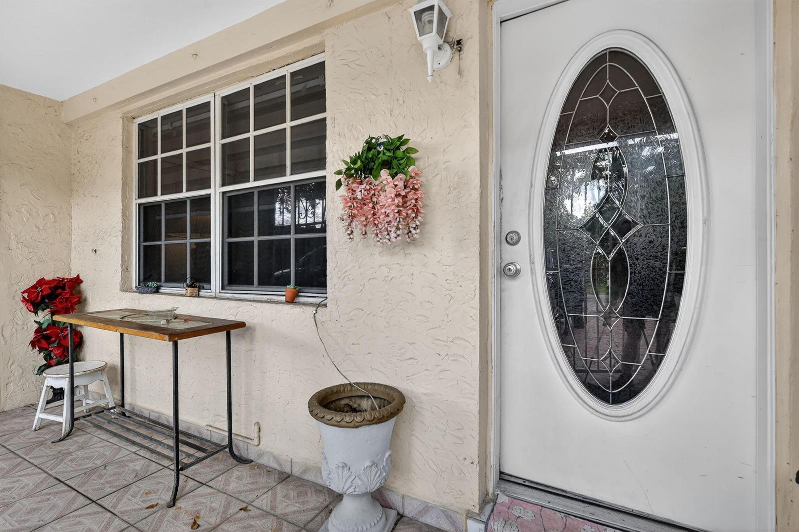 A covered porch features a white door with an oval glass insert and a window — 641 NE 140th Street, North Miami FL 33161, NORTH MIAMI, FL
