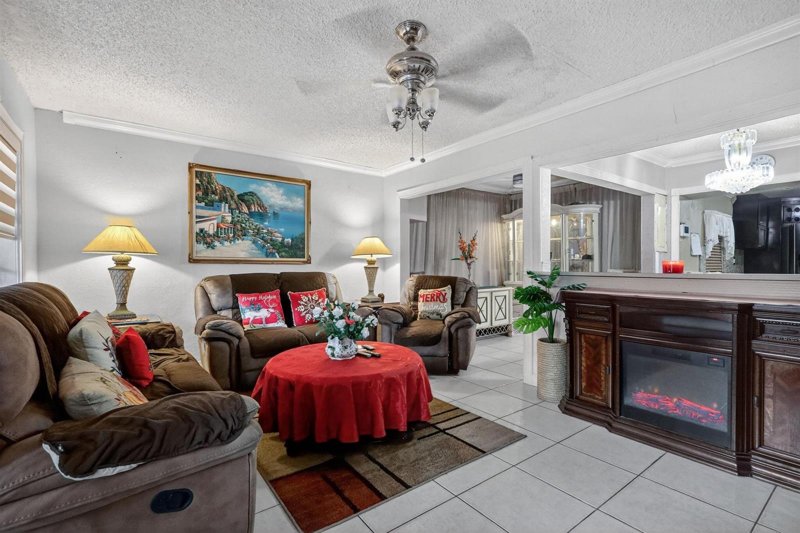 A living room features brown reclining furniture, a red-clothed round table, and an electric fireplace — 641 NE 140th Street, North Miami FL 33161, NORTH MIAMI, FL