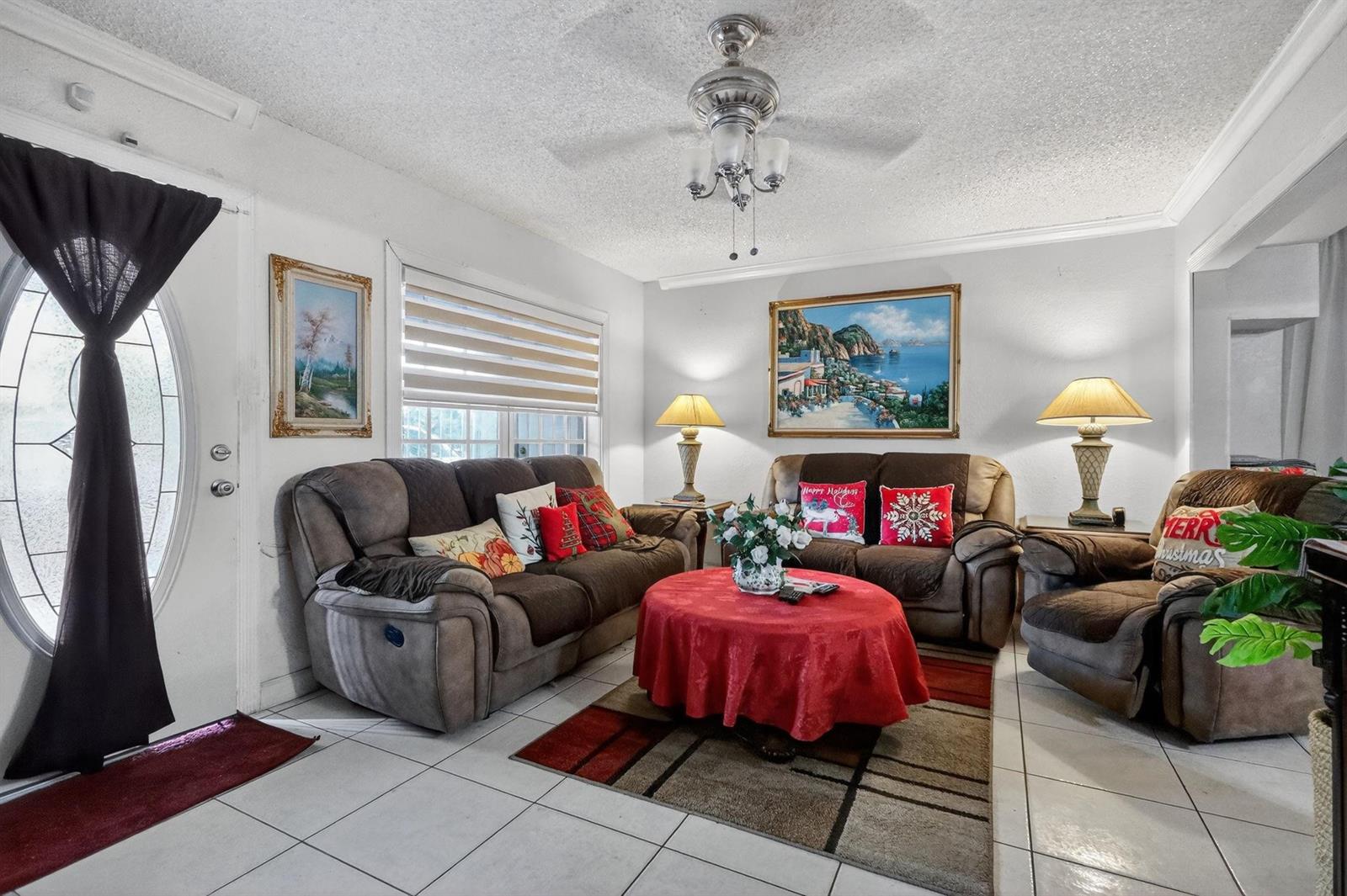 A living room features brown sofas, a red-covered round coffee table, and tiled flooring — 641 NE 140th Street, North Miami FL 33161, NORTH MIAMI, FL