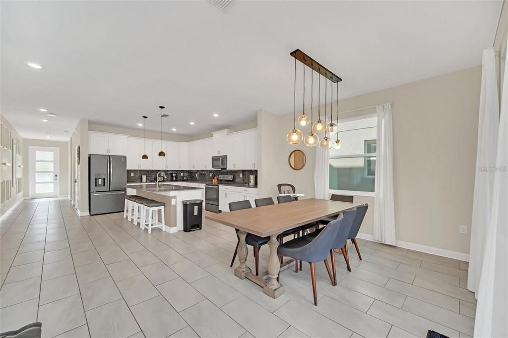 A modern open-concept kitchen and dining area with white cabinets, a kitchen island, and tile flooring — 2748 BOOKMARK DRIVE, KISSIMMEE, FL