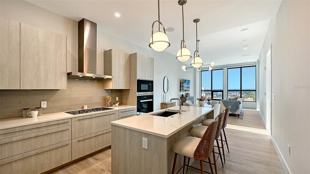 A modern kitchen features light wood cabinetry, a central island with bar seating, and floor-to-ceiling windows — 33 S PALM AVENUE UNIT 904, SARASOTA, FL