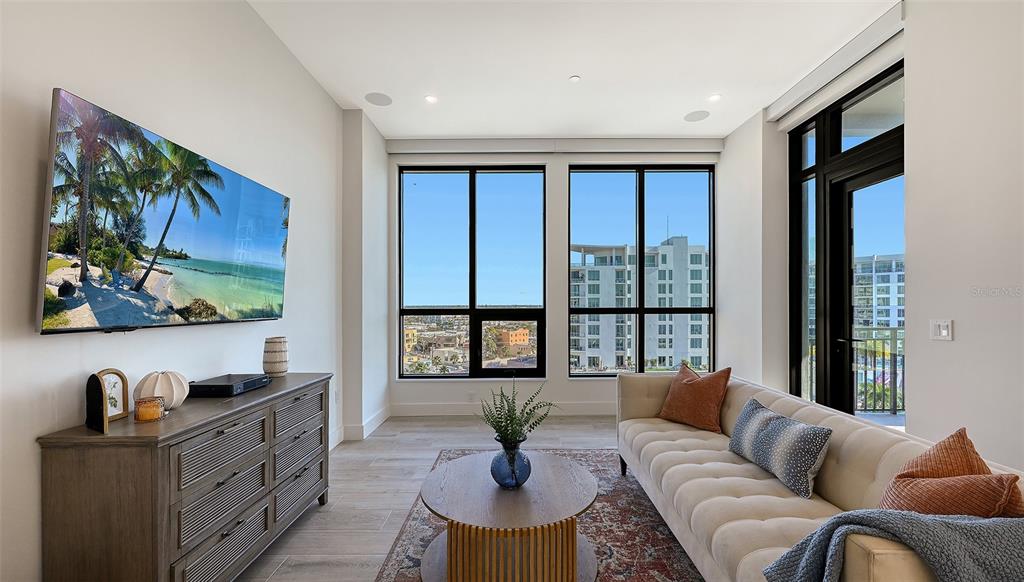 A living room features a large television, a beige sofa, and floor-to-ceiling windows — 33 S PALM AVENUE UNIT 904, SARASOTA, FL