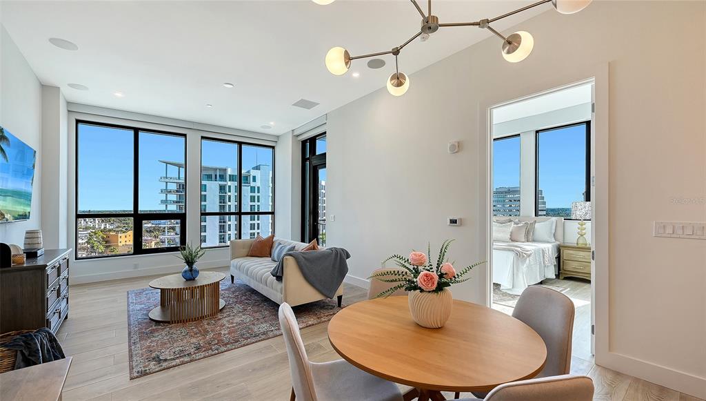 A modern living and dining area features light wood floors, a chandelier, and large windows — 33 S PALM AVENUE UNIT 904, SARASOTA, FL