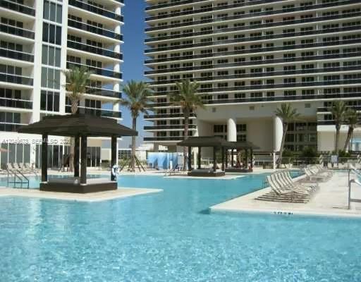 A swimming pool with cabanas sits in front of two large, modern high-rise buildings — 1800 S Ocean Dr # 1606, Hallandale Beach FL 33009, HALLANDALE BEACH, FL
