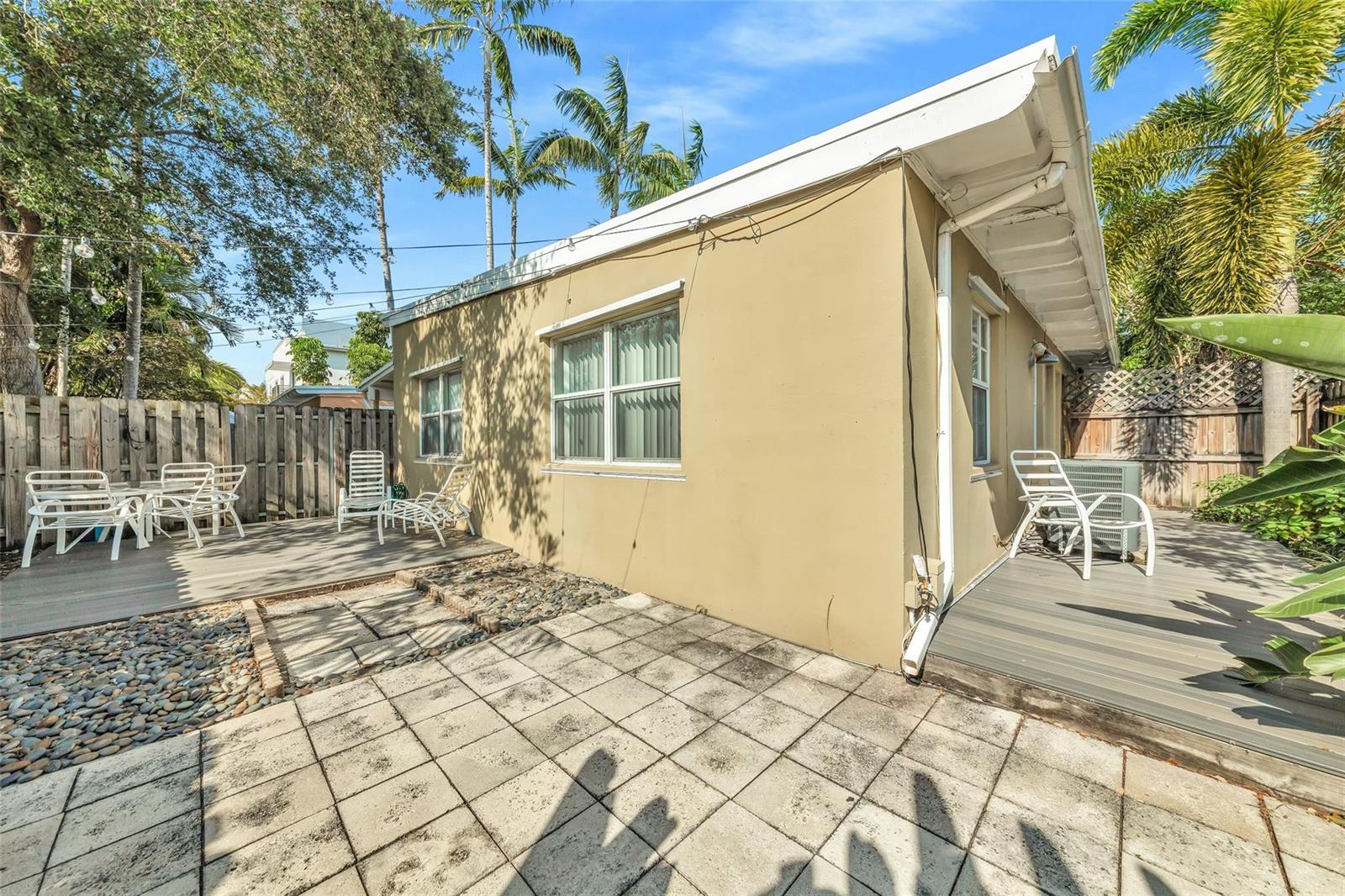 A tan exterior wall of a house features windows, a deck, and a paved patio area — 805 NE 17th Avenue # 4, Fort Lauderdale FL 33304, FORT LAUDERDALE, FL