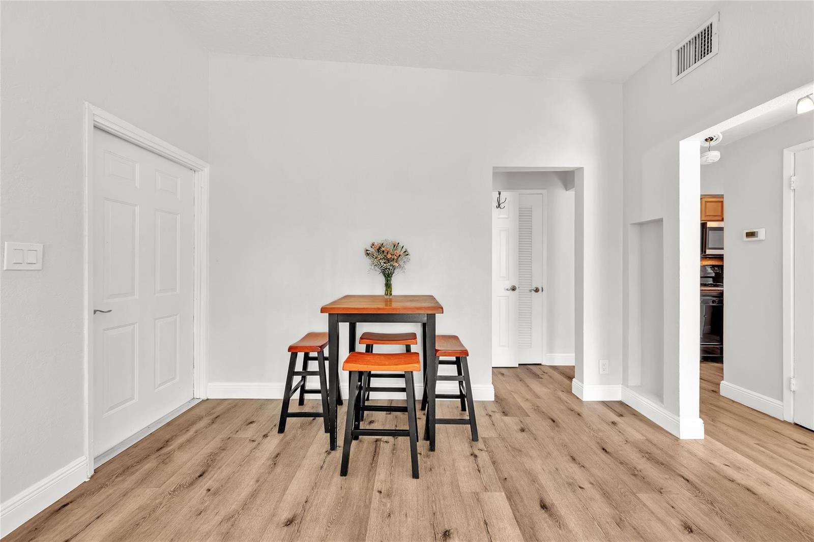 A dining area features a wooden table with four stools on light wood-look flooring — 805 NE 17th Avenue # 4, Fort Lauderdale FL 33304, FORT LAUDERDALE, FL