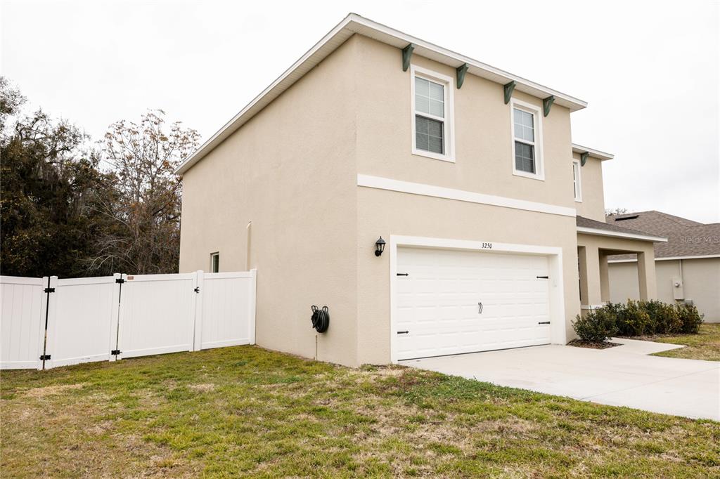 A two-story house with a beige stucco exterior and a white two-car garage — 3250 BLUE CRAB DRIVE, TAVARES, FL