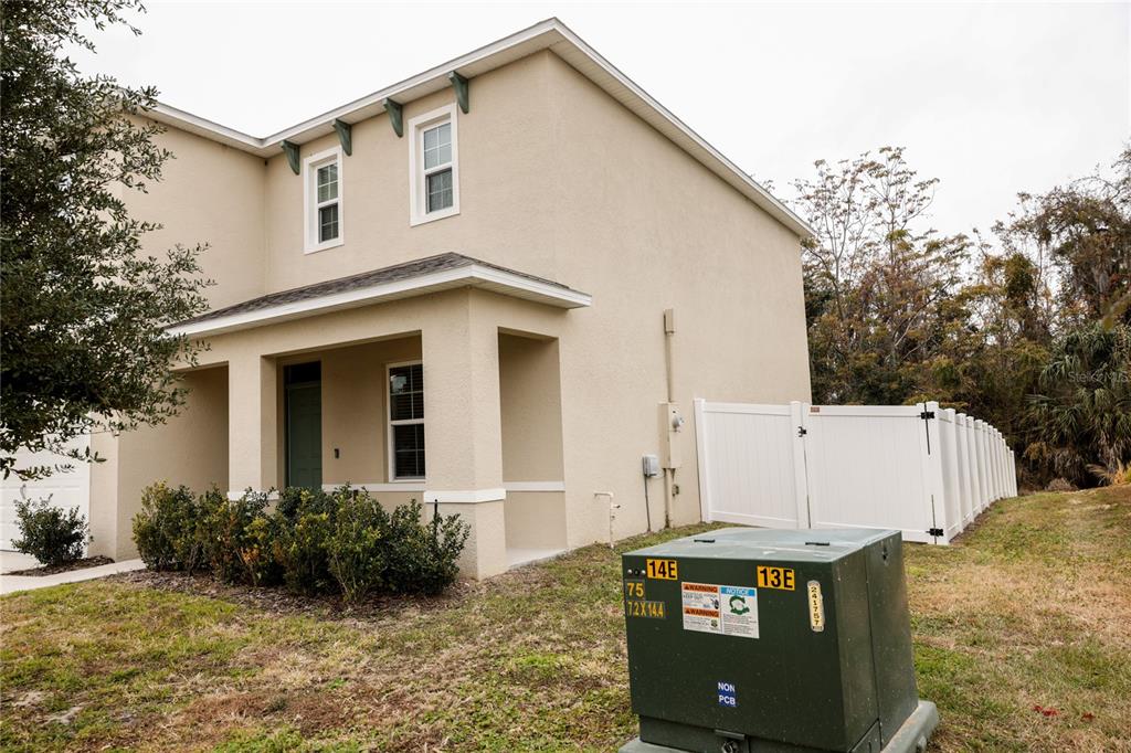 A two-story beige house features a front porch, a white vinyl fence, and a utility transformer — 3250 BLUE CRAB DRIVE, TAVARES, FL
