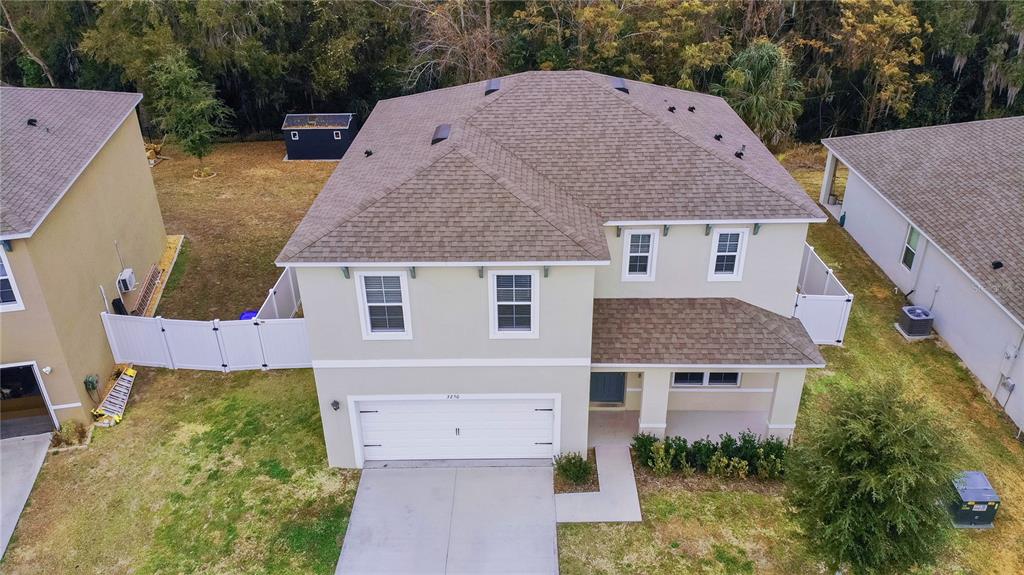 An aerial view shows a two-story suburban house with a tan exterior and shingled roof — 3250 BLUE CRAB DRIVE, TAVARES, FL