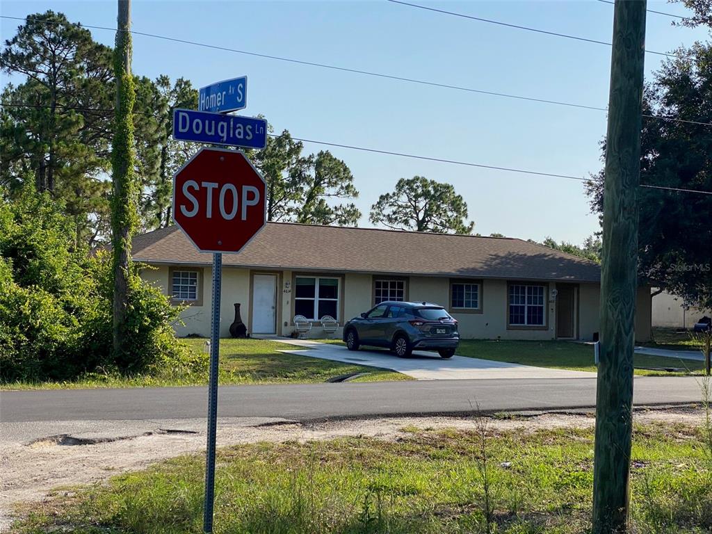 A single-story house with a driveway and a stop sign at a street intersection — 104 HOMER AVENUE S, LEHIGH ACRES, FL