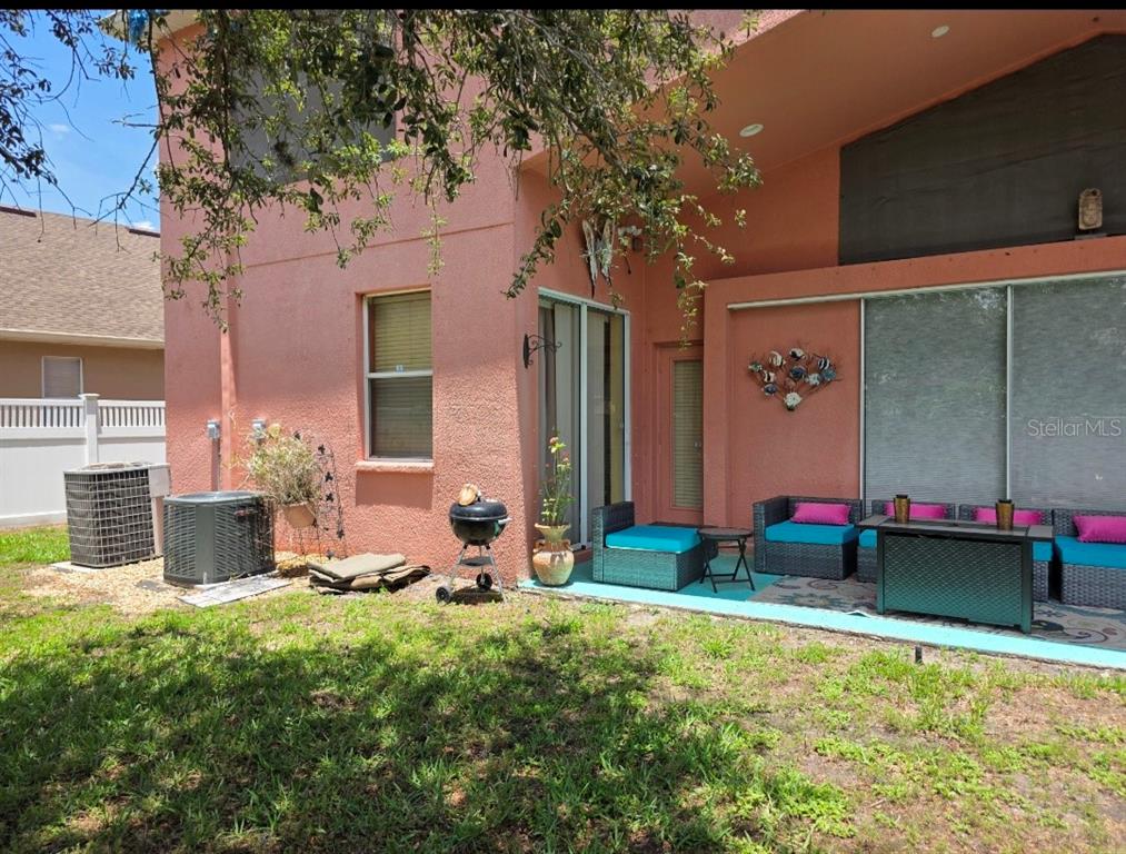 A pink stucco house exterior features a patio with outdoor furniture and two air conditioners — 12435 ADVENTURE DRIVE, RIVERVIEW, FL