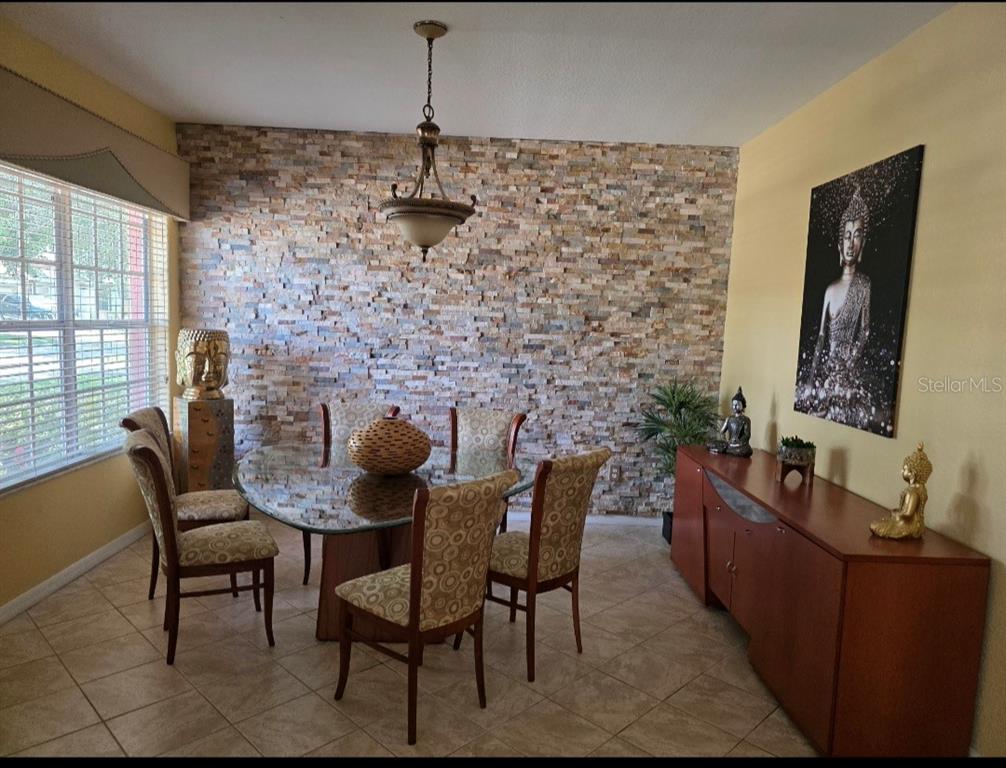 A dining room features a stone accent wall, a glass table, and Buddha-themed decor — 12435 ADVENTURE DRIVE, RIVERVIEW, FL