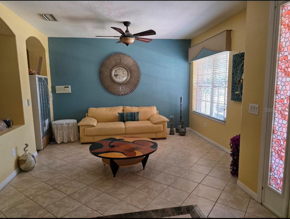 A living room features a yellow sofa, a round coffee table, and a blue accent wall — 12435 ADVENTURE DRIVE, RIVERVIEW, FL