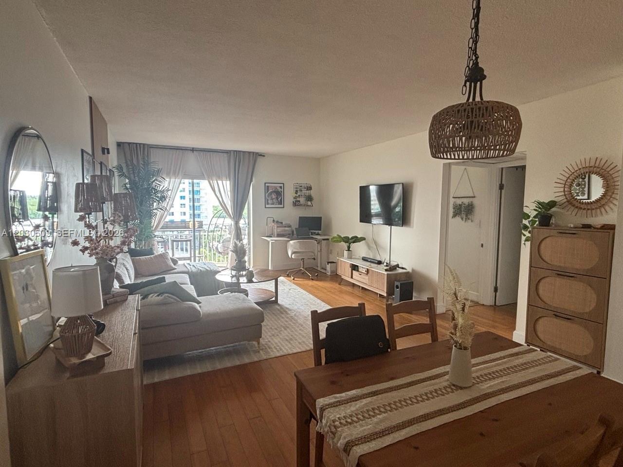 A living and dining area features hardwood floors, a sectional sofa, and a balcony view — 400 Kings Point Dr # 622, Sunny Isles Beach FL 33160, SUNNY ISLES BEACH, FL