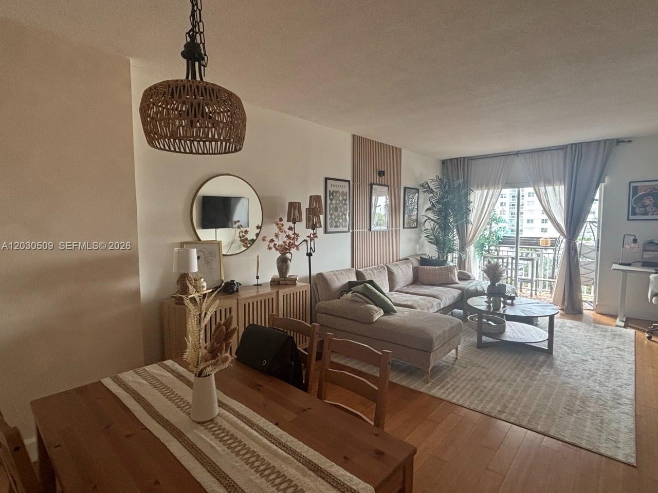 A living and dining area features a sectional sofa, wooden furniture, and a balcony view — 400 Kings Point Dr # 622, Sunny Isles Beach FL 33160, SUNNY ISLES BEACH, FL