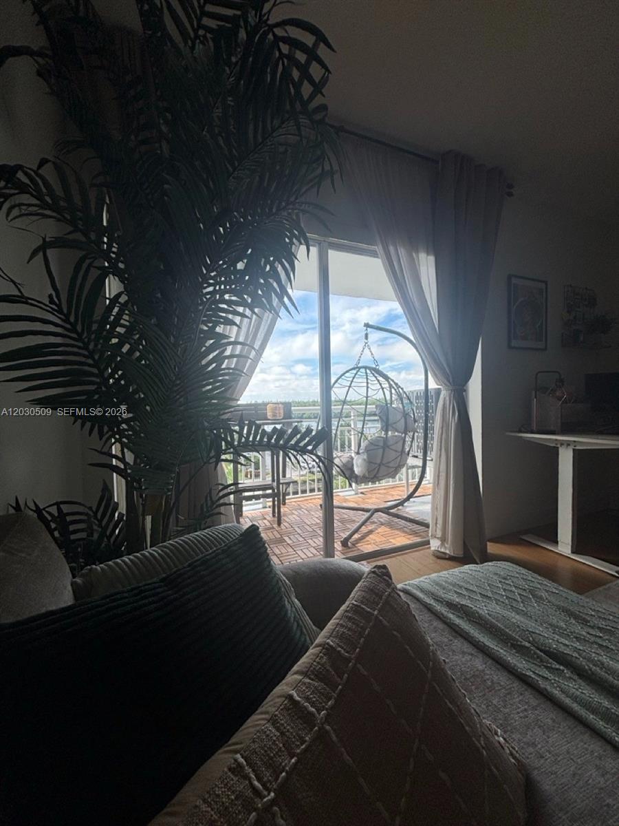 A living room features a large potted plant, a sofa, and a balcony with a swing — 400 Kings Point Dr # 622, Sunny Isles Beach FL 33160, SUNNY ISLES BEACH, FL