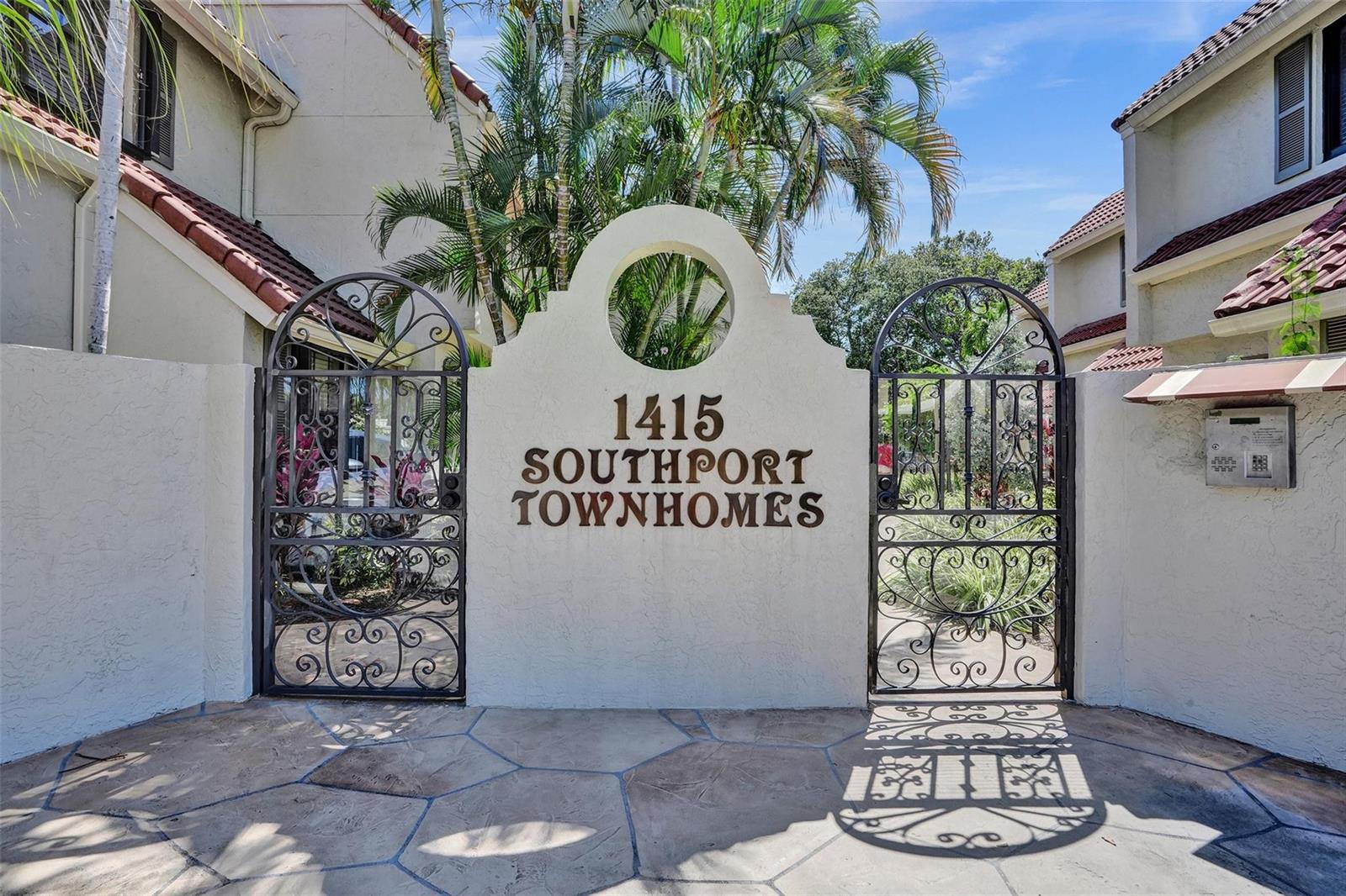 An arched stucco wall with metal gates marks the entrance to a townhome complex — 1415 Miami Road # B, Fort Lauderdale FL 33316, FORT LAUDERDALE, FL