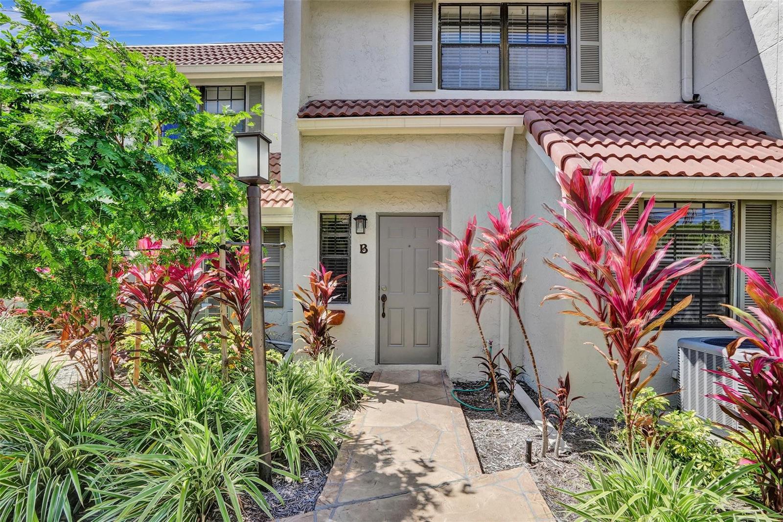 The exterior of a residential unit features a stone walkway, red-tiled roof, and tropical landscaping — 1415 Miami Road # B, Fort Lauderdale FL 33316, FORT LAUDERDALE, FL