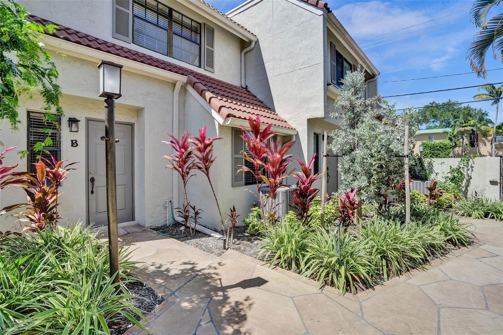 A stone walkway leads to the entrance of a two-story townhouse with red tile accents — 1415 Miami Road # B, Fort Lauderdale FL 33316, FORT LAUDERDALE, FL