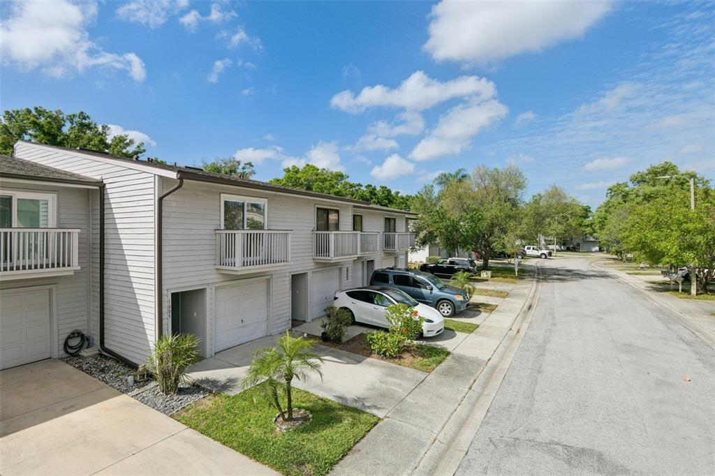 A row of two-story townhouses with light gray siding, balconies, and attached garages — 6436 92ND PLACE N UNIT 1005, PINELLAS PARK, FL