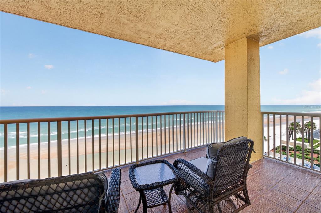 A balcony with wicker furniture overlooks a sandy beach and the ocean — 2901 S ATLANTIC AVENUE UNIT 603, DAYTONA BEACH, FL