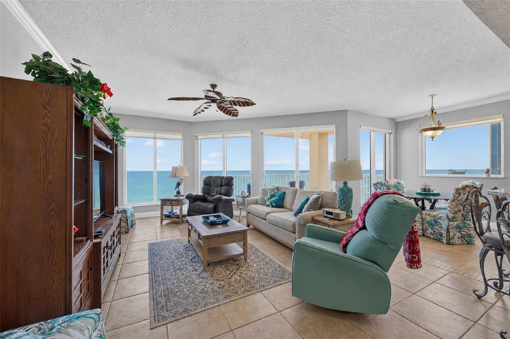 A living room with tile floors, a beige sofa, and large windows overlooking the ocean — 2901 S ATLANTIC AVENUE UNIT 603, DAYTONA BEACH, FL