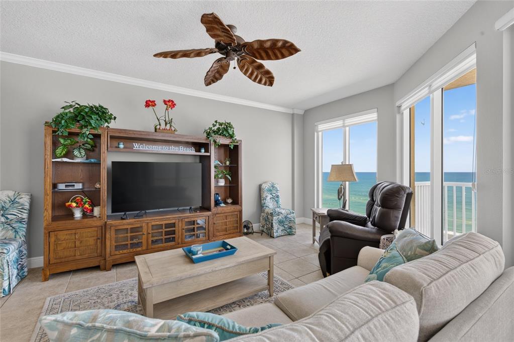 A living room features a wooden entertainment center, a ceiling fan, and ocean views — 2901 S ATLANTIC AVENUE UNIT 603, DAYTONA BEACH, FL