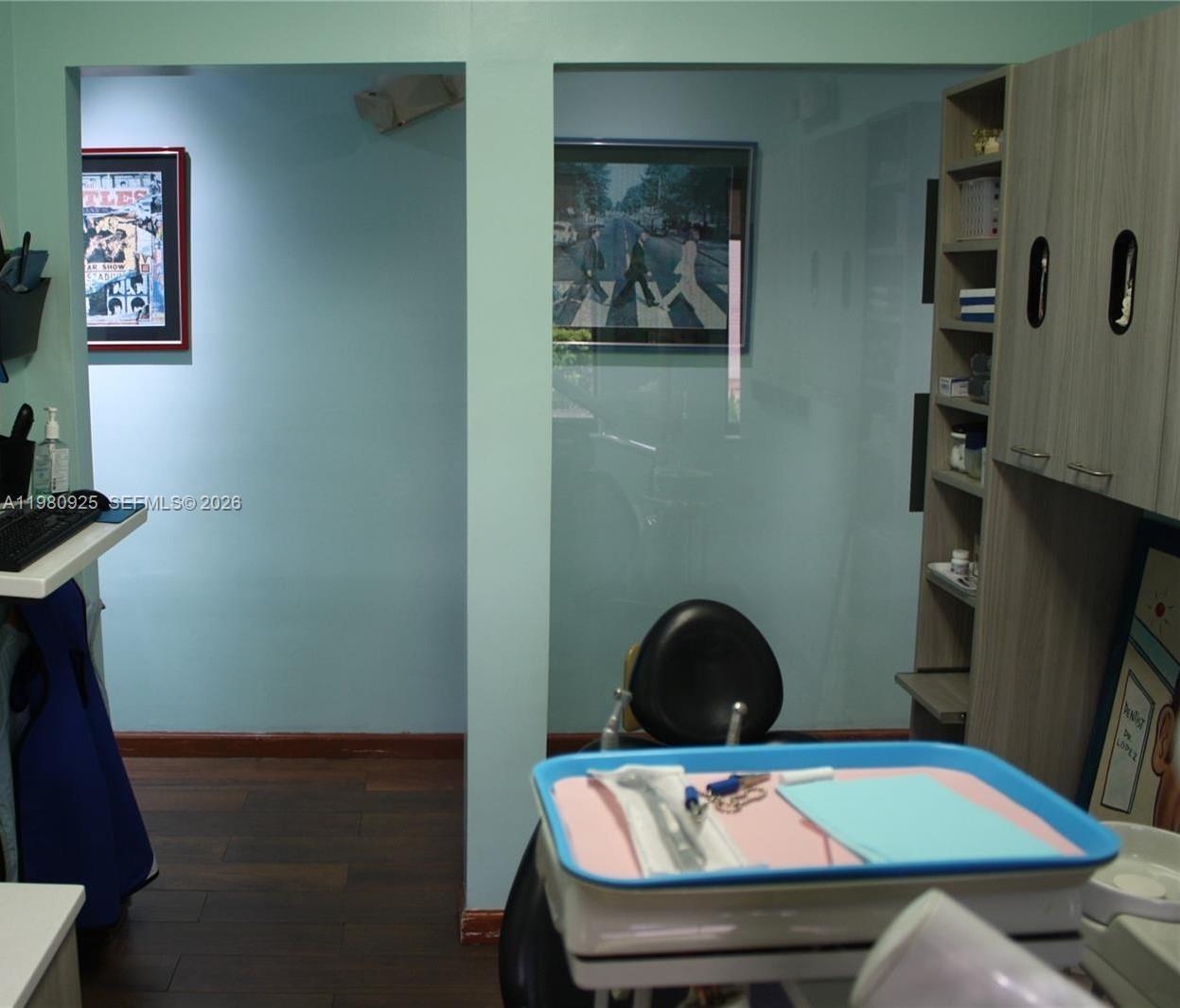 A dental exam room features light blue walls, wood flooring, and framed Beatles artwork — 1235 Alton Rd, Miami Beach FL 33139, MIAMI BEACH, FL