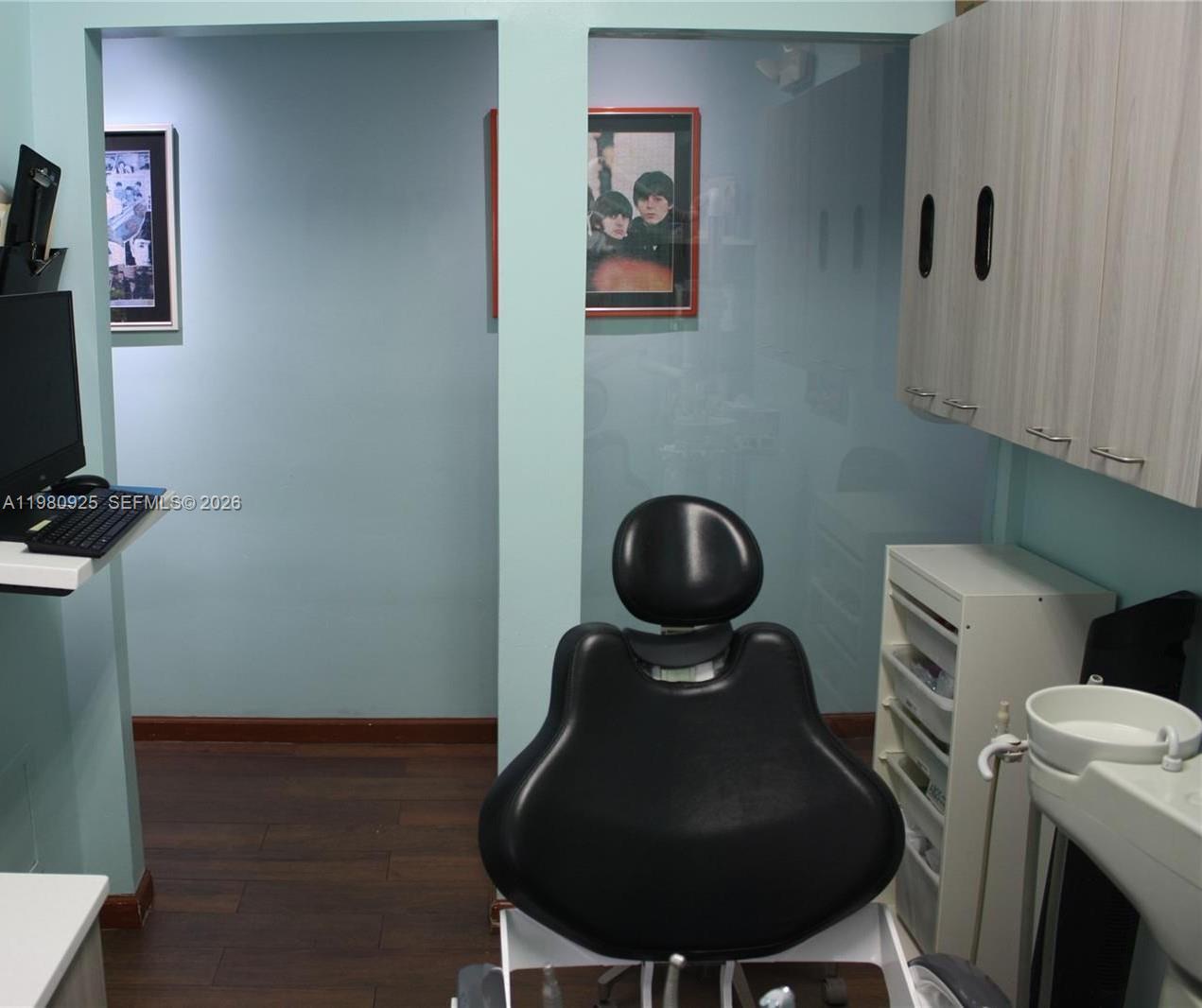 A dental examination room features a black chair, light blue walls, and wood-look flooring — 1235 Alton Rd, Miami Beach FL 33139, MIAMI BEACH, FL