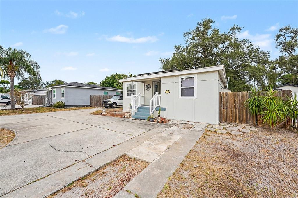 A single-story house with a concrete driveway, a small front porch, and a wooden fence — 1464 DRUID ROAD E, CLEARWATER, FL
