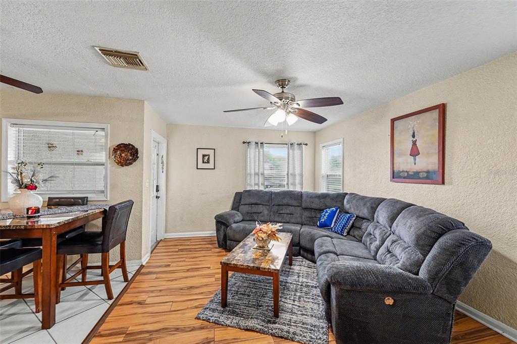 A living room features a grey sectional sofa, a coffee table, and wood-look flooring — 1464 DRUID ROAD E, CLEARWATER, FL