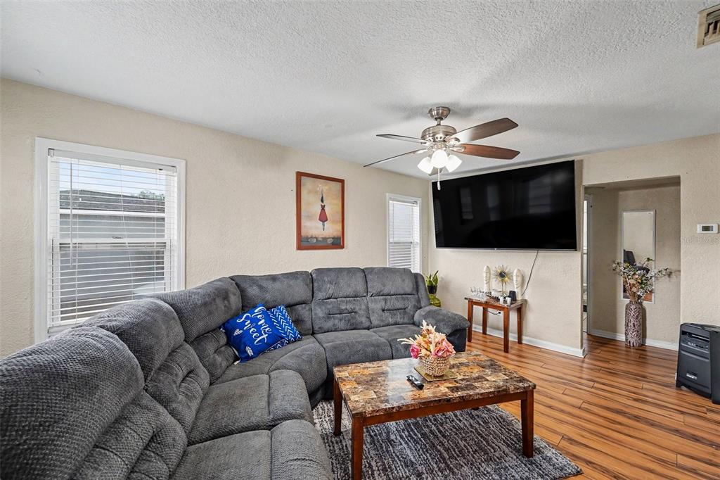 A living room features a gray sectional sofa, a marble-top coffee table, and a wall-mounted television — 1464 DRUID ROAD E, CLEARWATER, FL