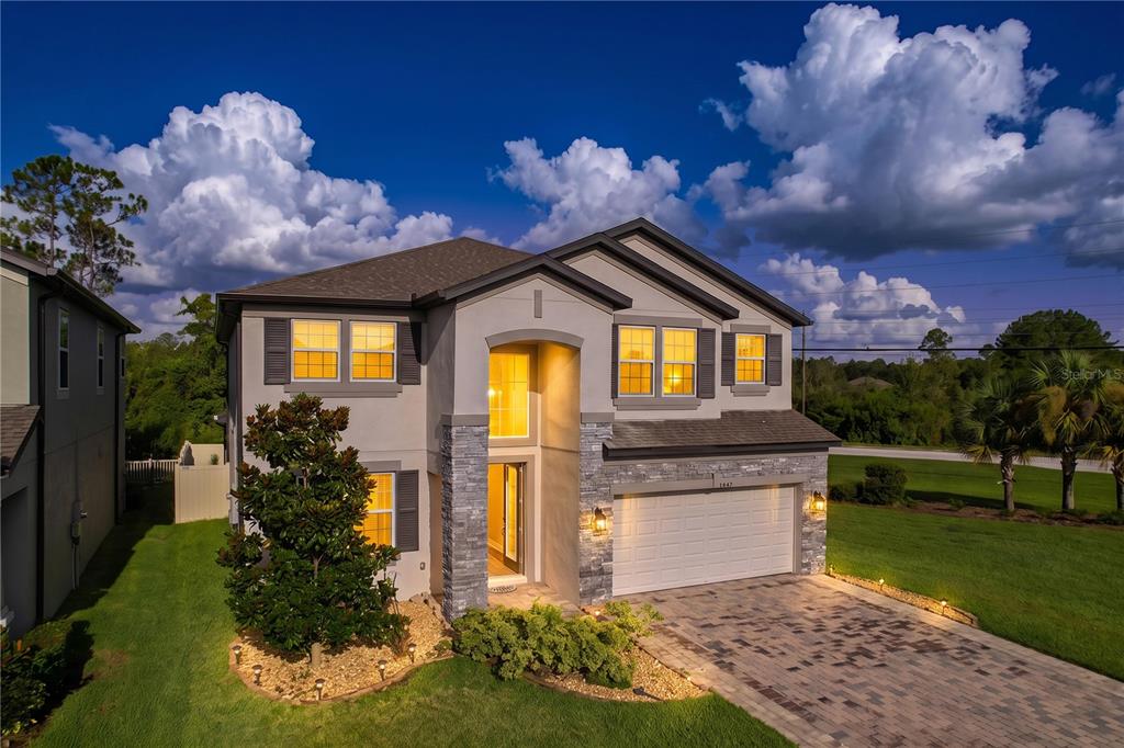 A two-story suburban house with a stone facade, a two-car garage, and a paved driveway — 22166 WOODMEN HALL, LAND O LAKES, FL