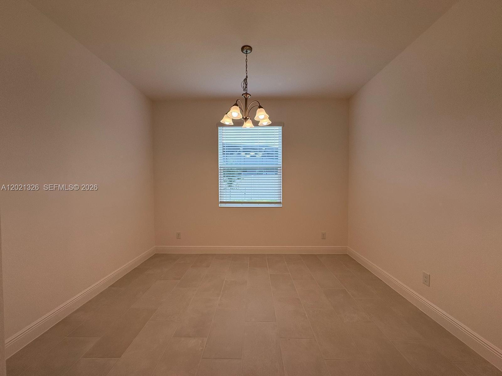 An empty dining room features light-colored tile flooring, white walls, and a central chandelier — 366 SWITCHGRASS LOOP # 366, Other City - In The State Of Florida FL 34715, OTHER CITY - IN THE STATE OF FLORIDA, FL