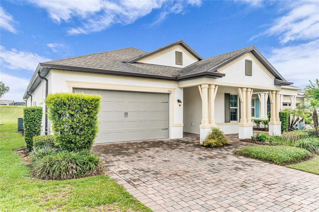 A single-story house with a beige stucco exterior, a two-car garage, and a palm tree — 1915 ESTUARY LANE, KISSIMMEE, FL