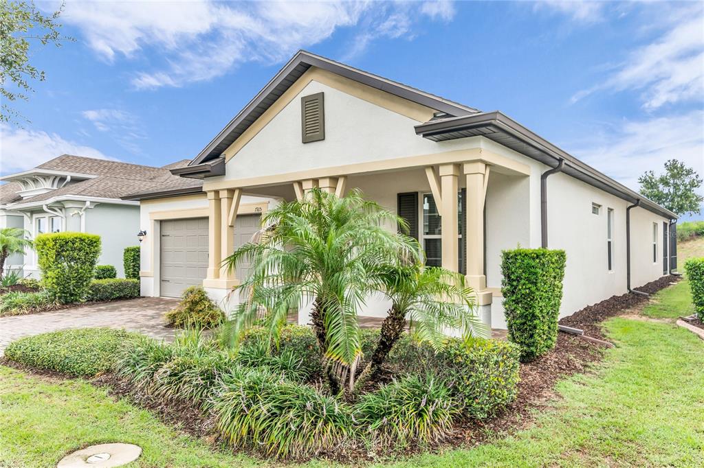 A covered brick entryway leads to a house exterior with columns and a shuttered window — 1915 ESTUARY LANE, KISSIMMEE, FL
