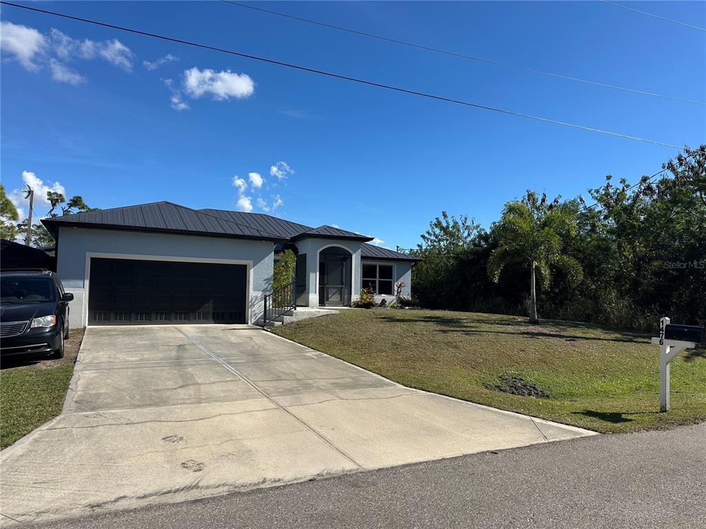 A single-story house with a dark metal roof, a two-car garage, and a concrete driveway — 1460 WESTOVER STREET, PORT CHARLOTTE, FL
