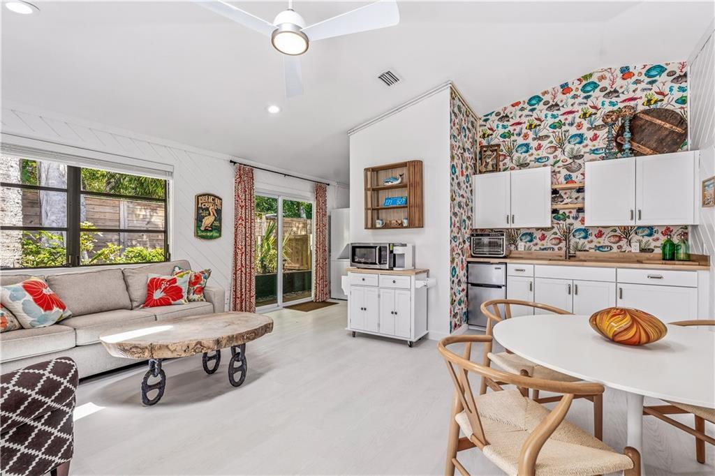 A living and dining area features white walls, wood-look flooring, and a colorful fish-patterned accent wall — VERO BEACH, FL