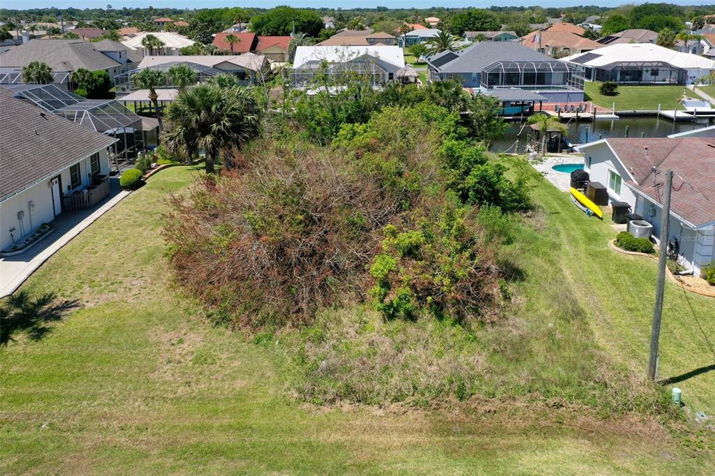 An elevated view of a vacant, overgrown residential lot situated between two houses and water — 17 CLARIDGE COURT N, PALM COAST, FL