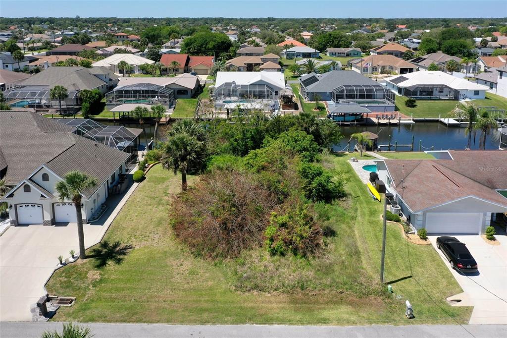An aerial view shows a vacant residential lot situated between two houses along a canal — 17 CLARIDGE COURT N, PALM COAST, FL